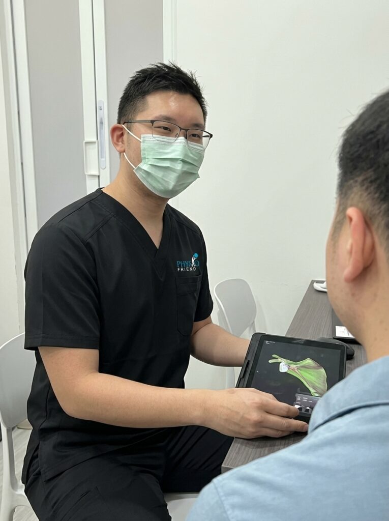 Goh Zhi Xun, founder and principal physiotherapist at Physio Friend Singapore, consulting with a patient